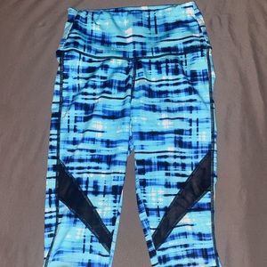 A pair of blue work out pants with sheer components & flexible material.